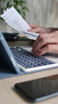 Person reviews financial documents and types on tablet keyboard while completing online application at quiet home workspace