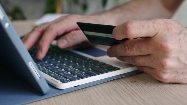 Person enters bank card details on tablet keyboard for online payment at home, close up of secure ecommerce purchase process