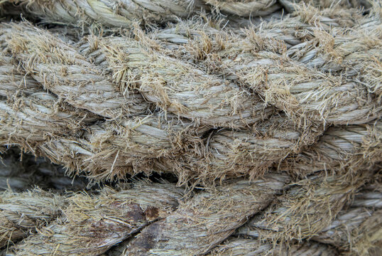 Detailed texture of worn marine rope showing frayed strands and signs of heavy usage in a maritime setting