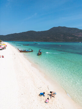 Vertical photo of Mother playing with kids on the beach in a beautiful beach with turquoise water in Koh Lipe Island, Thailand