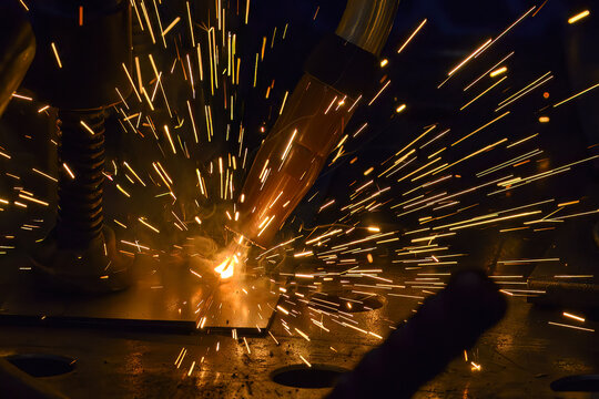 Close-up of sparkling light and bright sparks during an industrial high-precision laser welding process.