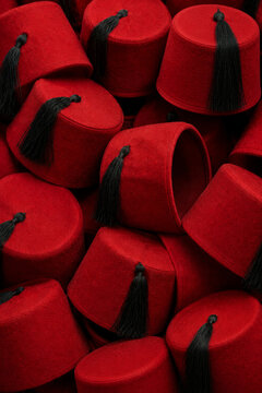 Collection of Traditional Moroccan Red Fez Hats with Black Tassels, Textured Background