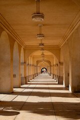 Sunlit arched corridor with repeating columns and patterned shadows