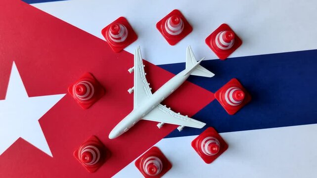 A mock up of airplane surrounded by no fly signs on a Cuba flag as a concept for a flight ban or cancellation