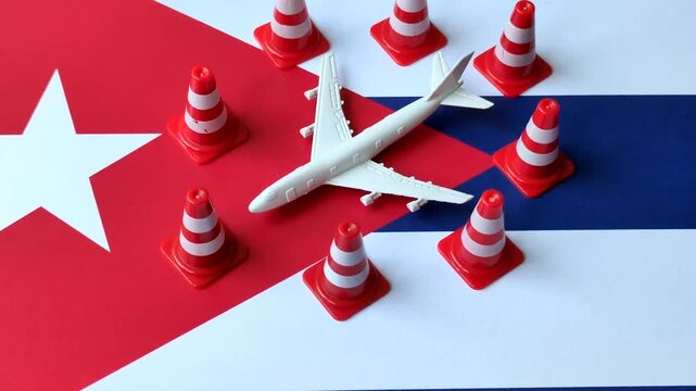 A mock up of airplane surrounded by no fly signs on a Cuba flag as a concept for a flight ban or cancellation