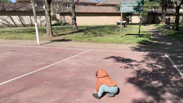 Toddler boy running and falling at playground court