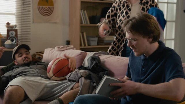 Diverse young adult roommates talking in messy college dorm room while female student cleaning up clothes and fighting. Student lifestyle, shared housing, and youth relationship marketing