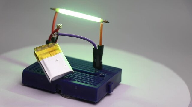 Vintage LED filament tube bulb powered by small battery on a breadboard circuit with details of the circuit