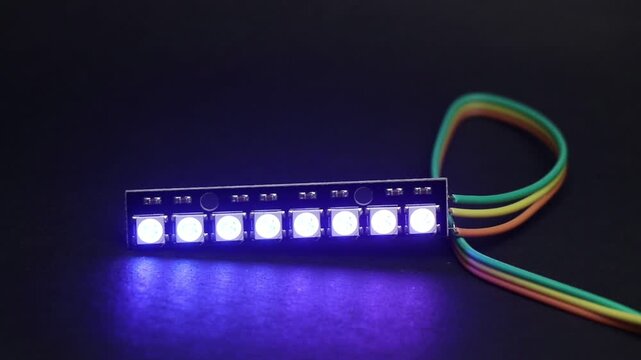 Addressable RGB LED strip with 8 individually controlled glowing LEDs displaying vibrant colors, operated by a microcontroller