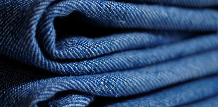 Folded stack of dark blue denim jeans fabric texture with material clothing background trousers workwear materiality wardrobe industry manufacture