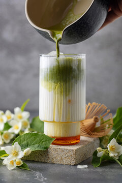 Green jasmine milk with macha tea in glass with jasmine flowers. Trendy drink