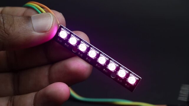 Hand holding an addressable RGB or ARGB LED strip light with individually controlled LEDs glowing in different colors