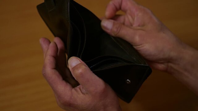 Man opens empty wallet showing lack of money and financial difficulties.
