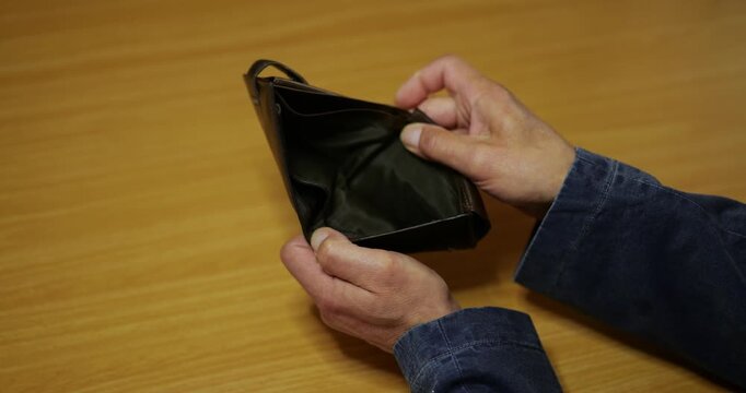 Man shows inside of empty wallet in close up view.