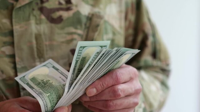 Military person putting US dollars into uniform pocket
