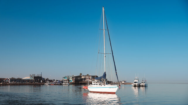 Walvis Bay, Namibia - May 26, 2025: Sailing boat anchors in calm waters of Walvis Bay Namibia under clear blue sky