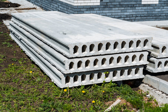 Premade Hollow Slabs With Circular Openings Placed Outside. Externally Stored Prefabricated Hollow Slabs Featuring Round Voids And Sunlight Texture Prepared For Construction Installation