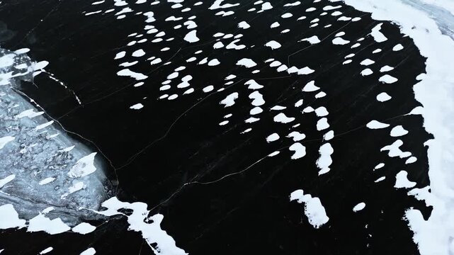 High angle view of winter frozen water surface with contrasting white snow patterns
