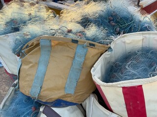 Fishing nets stacked in colorful bags, creating a textured seaside background © dvoevnore