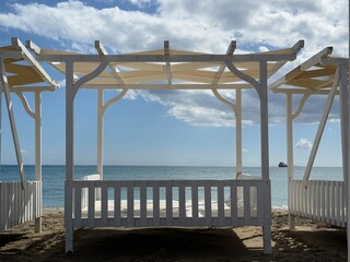Beachfront wooden gazebo with ocean view and partly cloudy sky, ideal for relaxation background © dvoevnore
