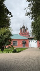 Russian orthodox church with onion domes in a garden setting surrounded by trees and pathway © dvoevnore