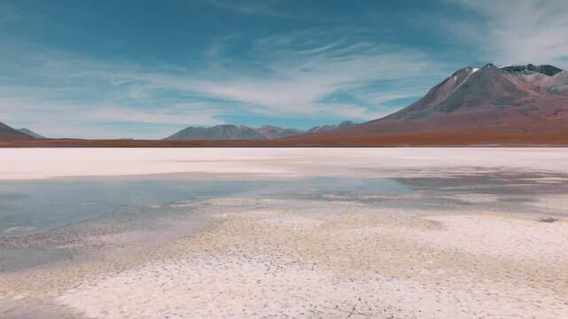 Aerial view of pink flamingos gathered on a high-altitude lagoon in Bolivia&rsquo;s Sud L&iacute;pez region, surrounded by volcanic landscapes and the Andes.
