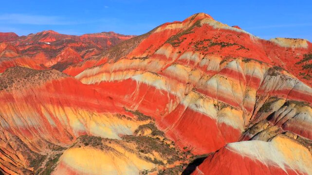 Aerial drone footage of layered red and orange Danxia mountain landforms in Zhangye Geopark, Gansu, China