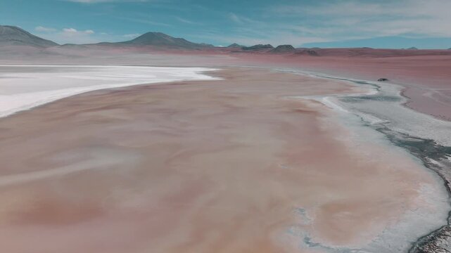 Aerial view of pink flamingos gathered on a high-altitude lagoon in Bolivia&rsquo;s Sud L&iacute;pez region, surrounded by volcanic landscapes and the Andes.