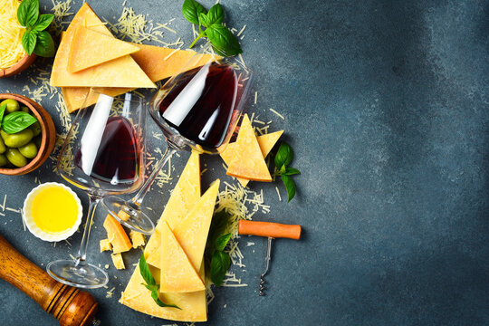 Pieces of hard aged cheese and glasses of red wine. Top view. Food background, free space for text.