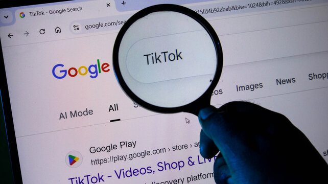 A person holding a magnifying glass over a computer screen showing a google search for tiktok