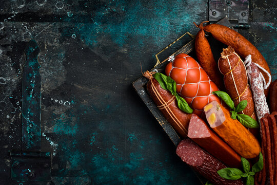 Set of different types of smoked salami and sausages in a wooden box. Close-up.