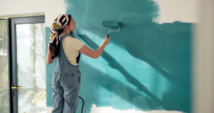 Woman, roller and painting in house with renovation project, interior design and property makeover. Back, creative person and art tools in living room with home improvement, diy or remodeling process