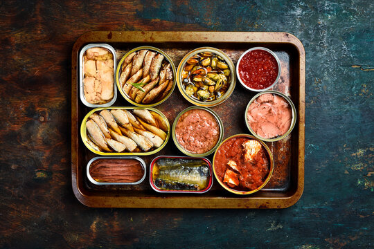 cans canned with different types of fish and seafood: fish, caviar, cod liver, sprats. Top view