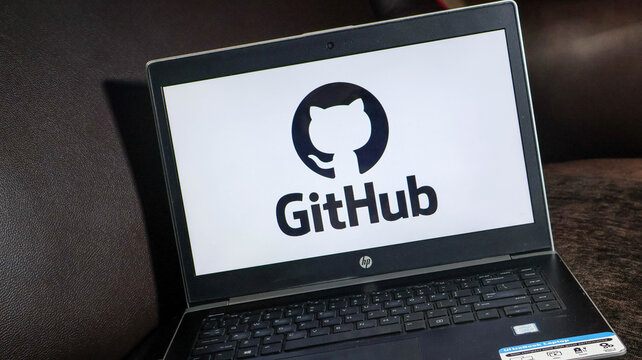 Laptop displaying github logo on screen sitting on brown surface