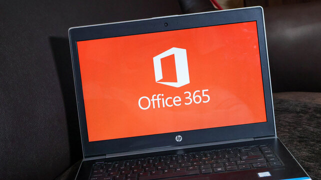 Laptop displaying the microsoft office 365 logo on its screen in a dark setting