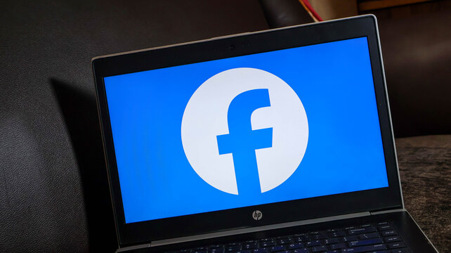 Facebook logo on a laptop computer screen with blue background and white circle