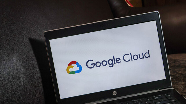 Laptop displaying google cloud logo on screen sitting on dark surface with black background