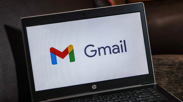 Laptop screen displaying gmail logo on a dark surface with keyboard visible