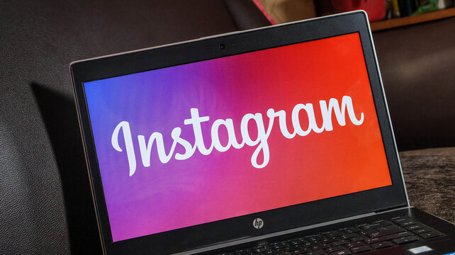 Closeup of hp laptop displaying instagram on screen in a cafe setting with colorful background