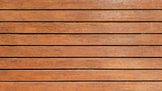 Wood deck planks forming a durable horizontal surface and natural background, showcasing warm brown tones and textured grooves, creating a strong wooden pattern