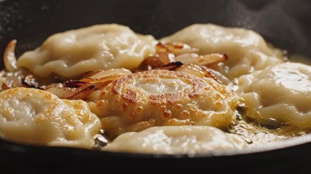 Frying traditional Polish pierogi dumplings in a hot pan with caramelized onions and butter