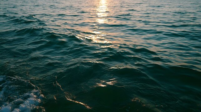 Emerald green ocean water reflects the warm golden light of the golden hour creating a serene and picturesque landscape