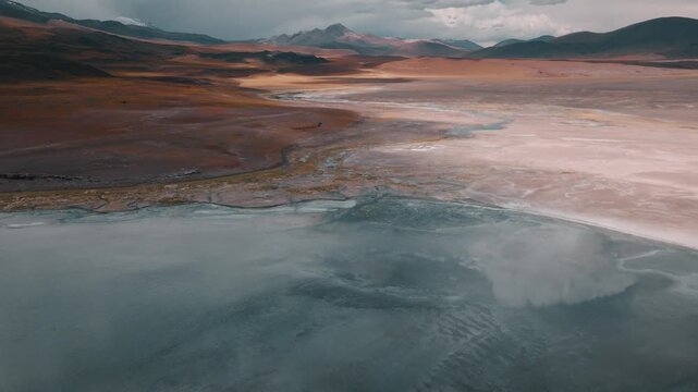 Aerial view of a high-altitude lagoon surrounded by volcanic mountains in Bolivia&rsquo;s Sud L&iacute;pez region. Reflections and dramatic skies enhance the Andean landscape.