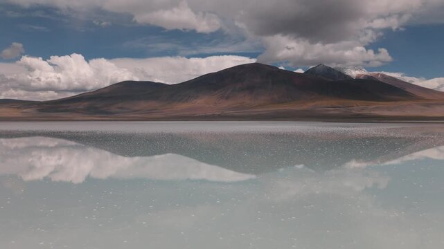 Aerial view of a high-altitude lagoon surrounded by volcanic mountains in Bolivia&rsquo;s Sud L&iacute;pez region. Reflections and dramatic skies enhance the Andean landscape.