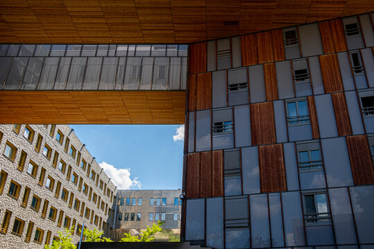 Timber overhang frames La Confluence architecture in Lyon, with facade panels, windows, courtyard, sky and residential buildings below