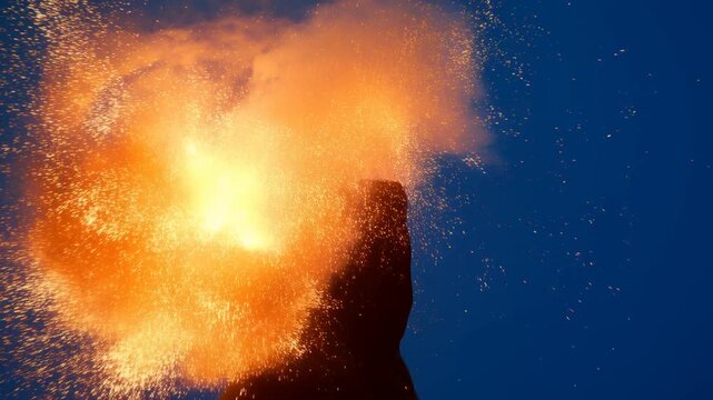 Static shot of silhouette head exploding into sparks and particles in blue studio backdrop side profile stationary portrait with fiery burst