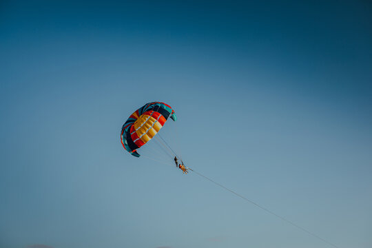 Parasailing in the golden sunset sky over the tropical sea water during summer vacation