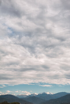 Snowcapped mountains rise beneath cloudscape