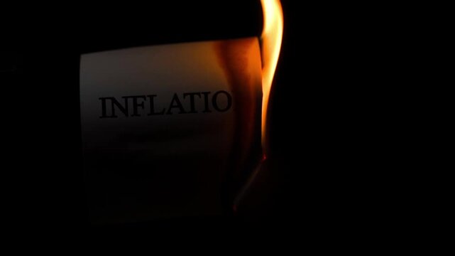 Burning paper with word inflation on dark background close-up