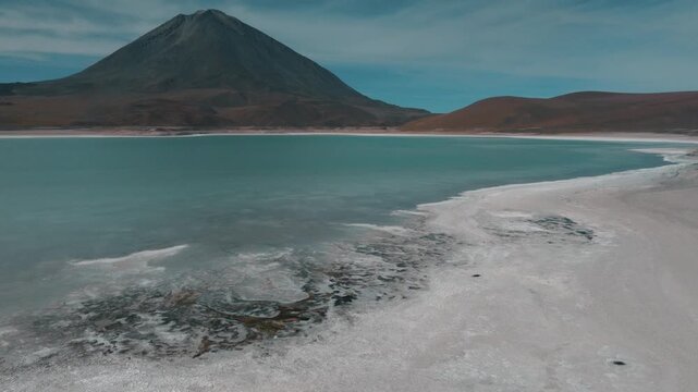Aerial view of a turquoise Andean lagoon surrounded by volcanic peaks in the remote landscapes of Bolivia&rsquo;s Sud L&iacute;pez region.